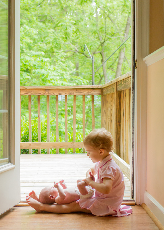 Newborn portraits: Baby with her big sister in the doorway of their new, empty house. Photography by Calm Cradle Photo & Design