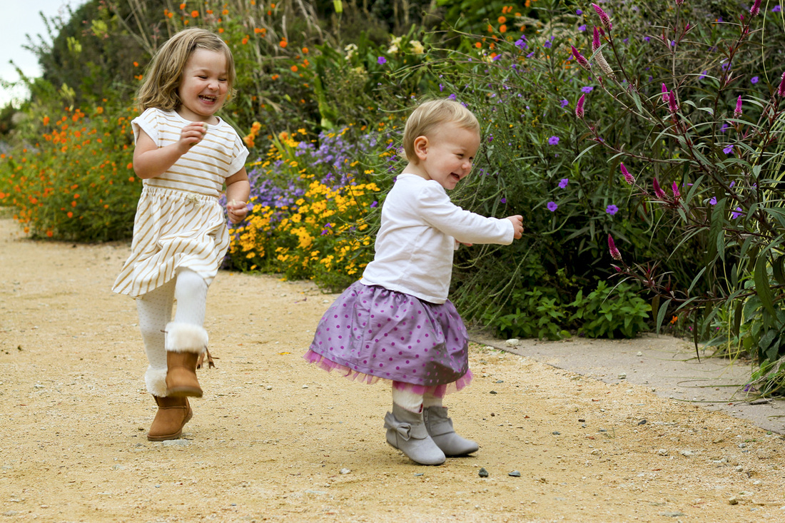 Toddler sisters dancing in the garden. By Calm Cradle Photo & Design