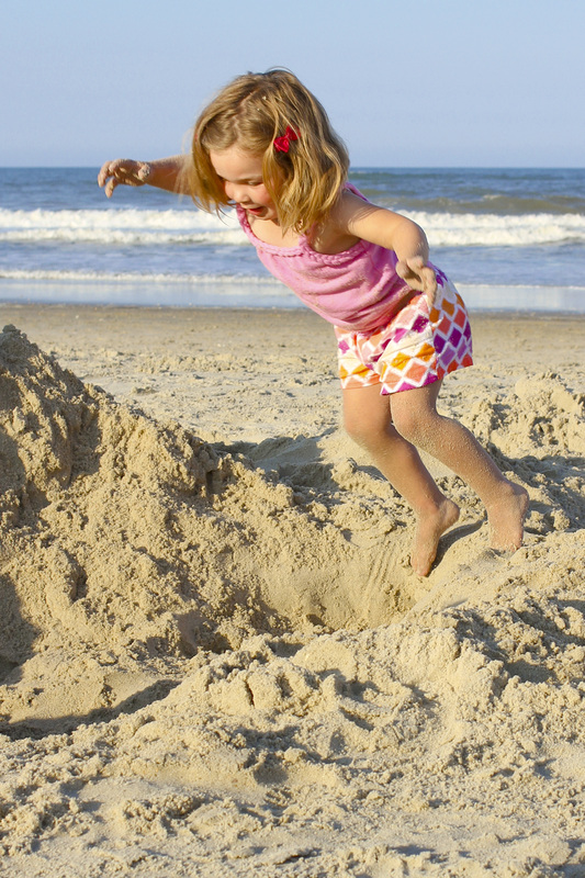 Jump! Little girl jumping into the sand at the beach. By Calm Cradle Photo & Design